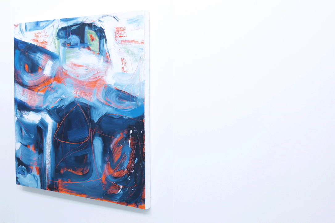 Artwork made up primarily of blue and white brushstrokes with orange wisps hanging on a plain wall.