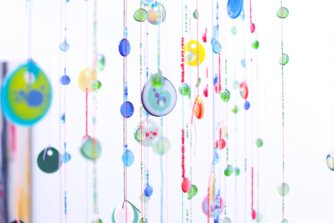 Multicoloured buttons made into artwork, hung on strings and beads.